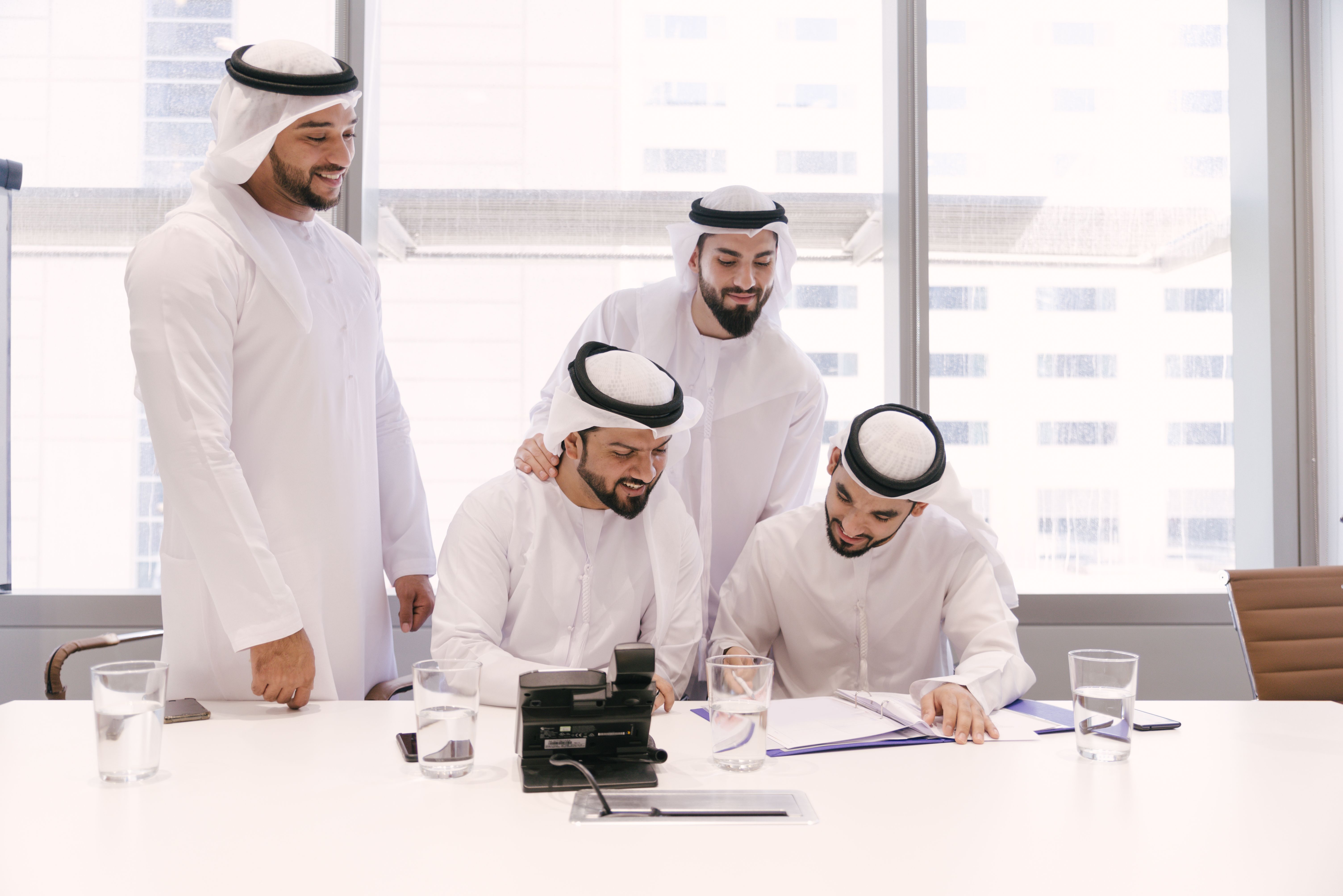 Middle Eastern corporate executives reviewing legal documents for company formation in Dubai. This represents the notarization of the Memorandum of Association (MOA) and the final steps of obtaining a trade license from the Department of Economy & Tourism (DET) in 2026.